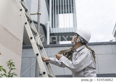 工事現場イメージ 建物を調査するビジネスマン はしごを登るの写真素材