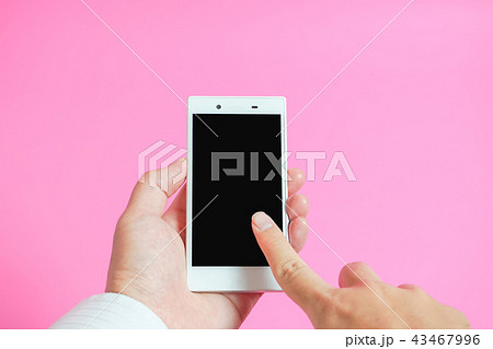 スマートフォンを使う手 ピンク色背景 スマートフォンを使う手 ピンク色背景 43467996