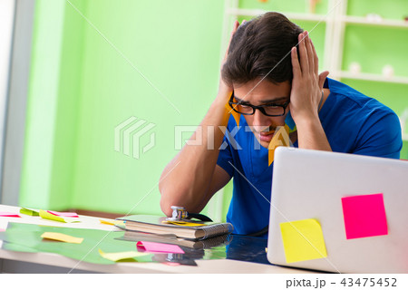 Young doctor sitting in hospital with many conflicting prioritie 43475452