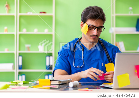 Young doctor sitting in hospital with many conflicting prioritie 43475473