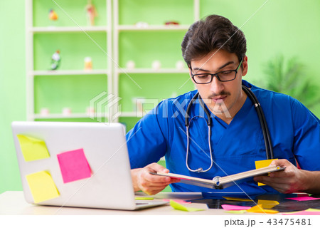 Young doctor sitting in hospital with many conflicting prioritie 43475481