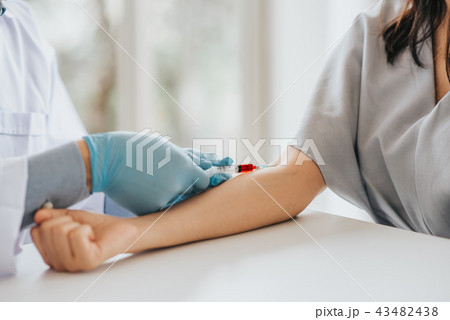 Doctor using syringe takes blood from patient arm Doctor using syringe takes blood from patient arm 43482438