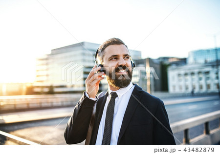 Hipster businessman with headphones in the city, listening to music. Hipster businessman with headphones in the city, listening to music. 43482879