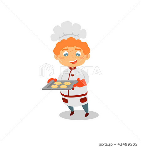 Cute red-haired boy holding tray with fresh-baked cookies. Future job. Kid in chef hat and uniform Cute red-haired boy holding tray with fresh-baked cookies. Future job. Kid in chef hat and uniform 43499505