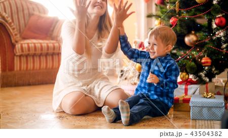 Portrait of happy laughing toddler boy throwing colorful confetti with mother on Christmas morning 43504382