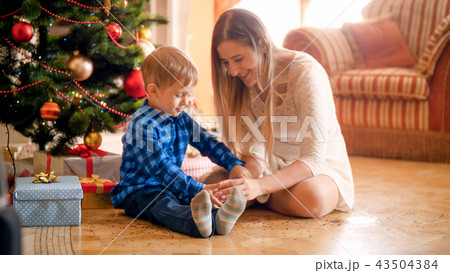 Cute little boy with mother on Christmas morning sitting at living room 43504384