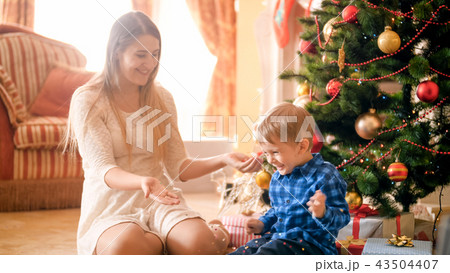 Laughing happy toddler boy with mother throwing colorful confetti on Christmas morning Laughing happy toddler boy with mother throwing colorful confetti on Christmas morning 43504407