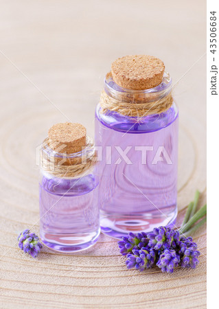 lavender oil in glass bottles and fresh lavender flowers on stump and wooden background 43506684