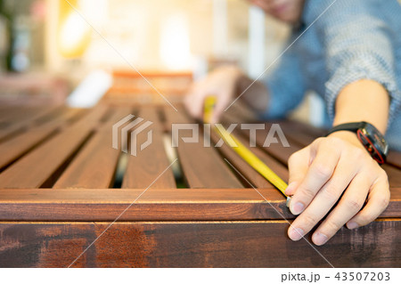 Asian man using tape measure on wooden table Asian man using tape measure on wooden table 43507203