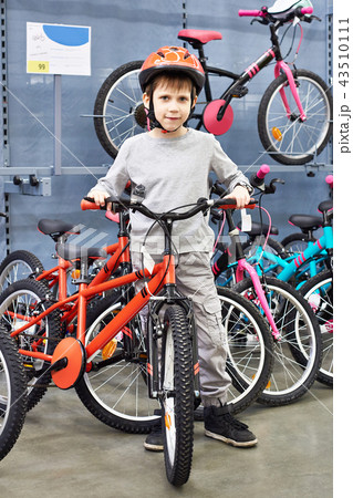 Boy in helmet chooses with bicycle in sport shop Boy in helmet chooses with bicycle in sport shop 43510111