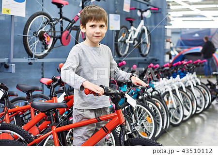 Boy chooses bicycle in sport store Boy chooses bicycle in sport store 43510112