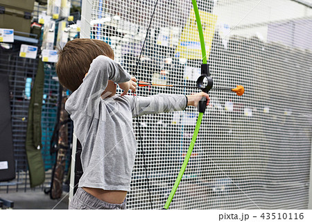 Little boy shoots by bow in children's shooting range Little boy shoots by bow in children's shooting range 43510116