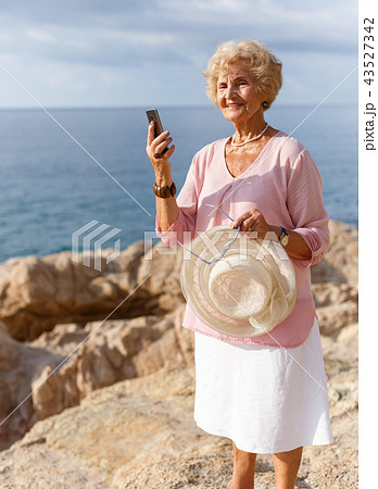 Elderly woman using phone at seaside Elderly woman using phone at seaside 43527342