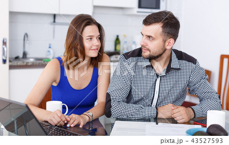 Young family couple looking at laptop at kitchen table at home 43527593