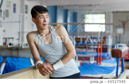Positive young man asian acrobat posing at modern sport gym 43527595