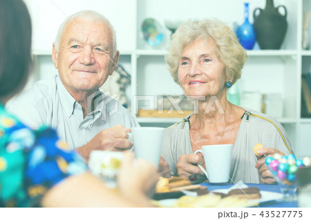 Smiling elderly spouses enjoying tea with girl Smiling elderly spouses enjoying tea with girl 43527775