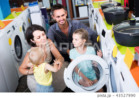 parents with two kids choosing washing machine in home appliance store parents with two kids choosing washing machine in home appliance store 43527990