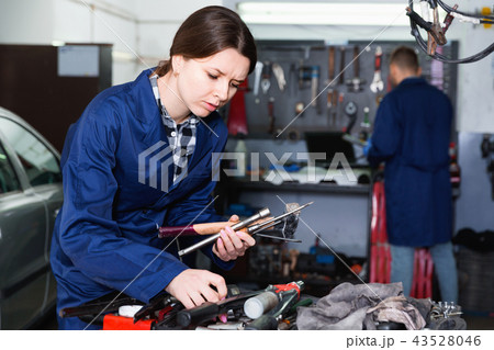 Young woman master is choosing instruments for work in workshop. Young woman master is choosing instruments for work in workshop. 43528046