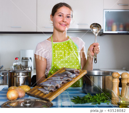 Woman preparing small fish indoors. 43528082