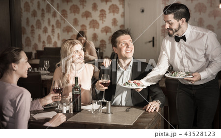 Waiter bringing delicious salads to visitors of restaurant 43528123