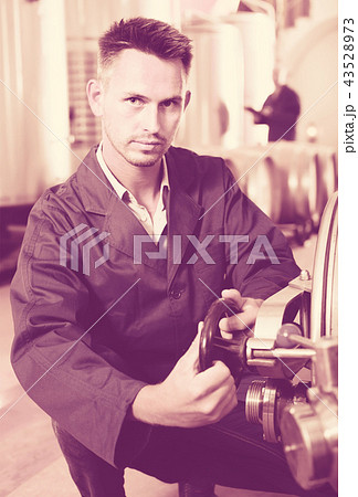 young calm man machinery operator working in winery 43528973
