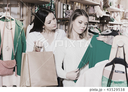Young smiling female friends choosing fashion green pullover Young smiling female friends choosing fashion green pullover 43529538