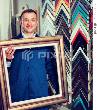 Man worker holding picture frame details on counter 43529729