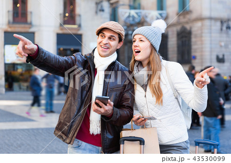 Couple at the historical city center with mobile phones pointing finger 43530099