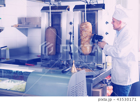 mature chef slicing kebab in fast food. mature chef slicing kebab in fast food. 43530171
