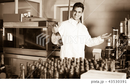 Adult male holding newly produced bottle of wine Adult male holding newly produced bottle of wine 43530391
