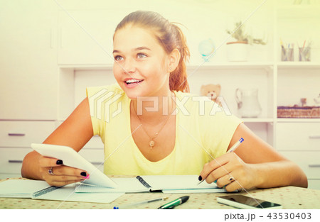 girl with smartphone doing homework . 43530403