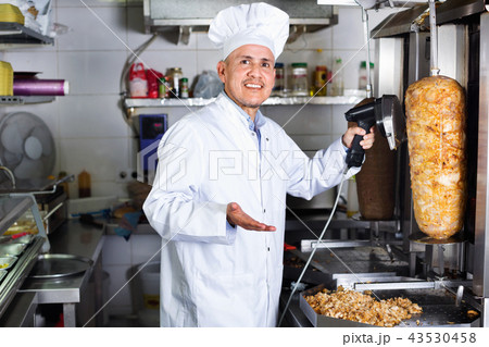 Cheerful mature man cook cutting kebab meat on kitchen Cheerful mature man cook cutting kebab meat on kitchen 43530458