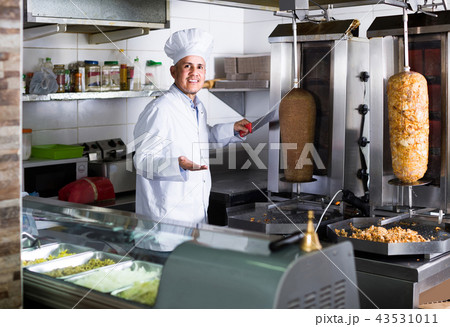man chef wearing uniform cutting meat for kebab on kitchen in fast food restaurant 43531011