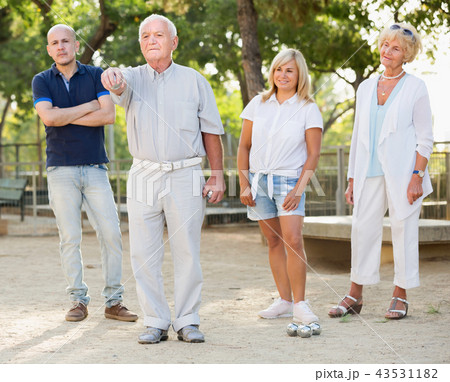 Mature man with friends playing petanque in park Mature man with friends playing petanque in park 43531182