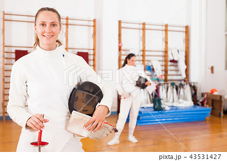 Smiling young female in uniform standing at fencing room Smiling young female in uniform standing at fencing room 43531427