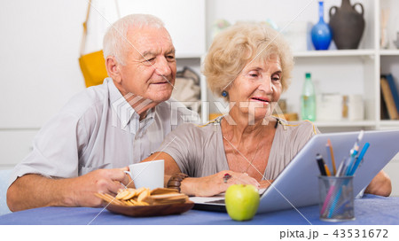 Smiling senior couple surfing net with laptop Smiling senior couple surfing net with laptop 43531672