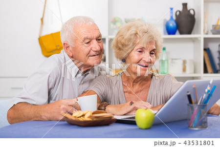 Cheerful mature spouses using laptop at home 43531801