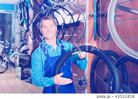 Seller in uniform picking new bicycle wheel in hands 43531858