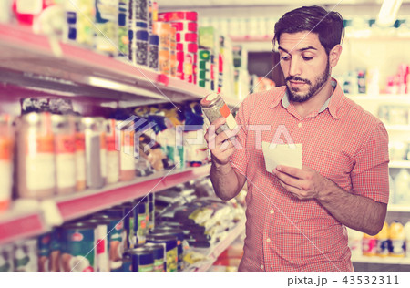 Man is choosing Oregano using note list in supermarket. 43532311