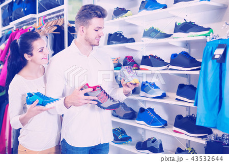 loving couple deciding on new sneakers in sports store 43532644