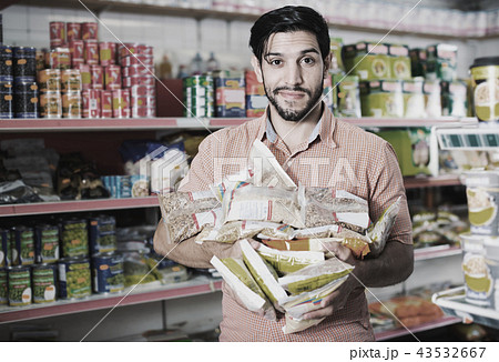 Smiling male is posing with purchases near shelves in supermarket. 43532667