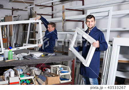 Production workers in coverall with different finished PVC profiles and windows at factory Production workers in coverall with different finished PVC profiles and windows at factory 43533267