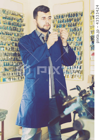male worker shaping new key in repair workshop 43533424