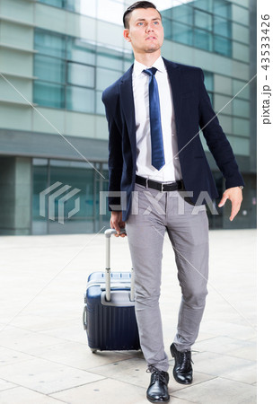 Adult man in suit with suitcase is staying Adult man in suit with suitcase is staying 43533426