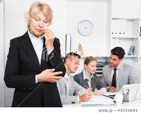 Business woman crying in office with working colleagues Business woman crying in office with working colleagues 43533693