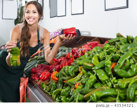 woman in uniform selling paprika on fruit market 43534321