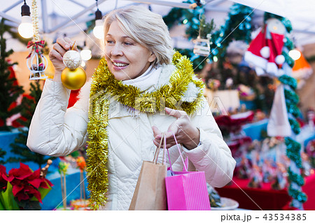 Positive mature female buying decoration at Christmas Fair 43534385