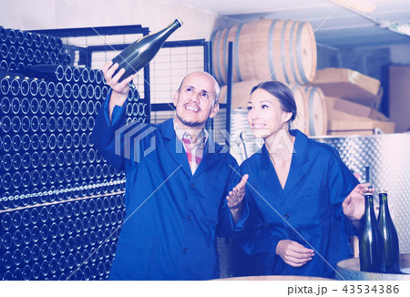 man and women coworkers looking at bubbly wine in bottle standin man and women coworkers looking at bubbly wine in bottle standin 43534386