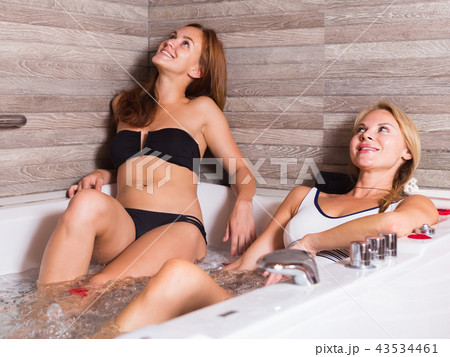 Two girl are resting in bath with red petals Two girl are resting in bath with red petals 43534461