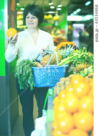 Middle aged woman with basket choosing fruits 43534968